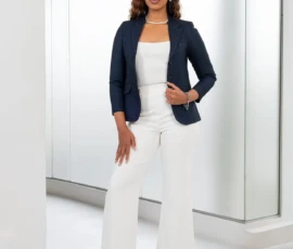 Sophisticated navy tailoring paired with classic white trousers for the modern professional. A woman wearing a sophisticated navy tailored blazer and white wide-leg trousers by K&R Thread.